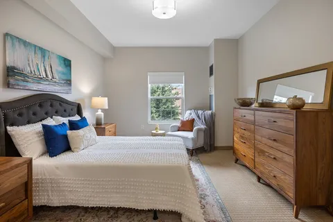 Bedroom with a patterned bedspread, dresser and a large mirror