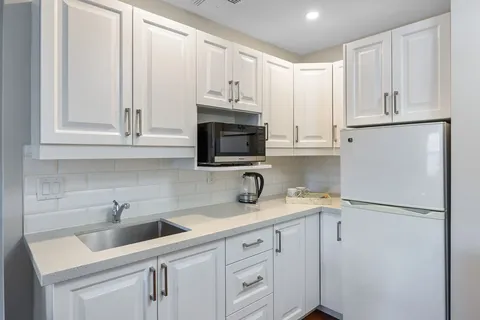 White kitchenette with a sink, microwave and refrigerator
