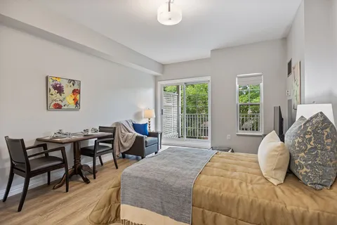 Bed beside a small dining table and glass balcony doors