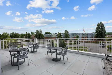 Raised patio with metal tables, chairs and a white railing