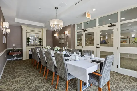 Long dining table with patterned chairs beneath a chandelier