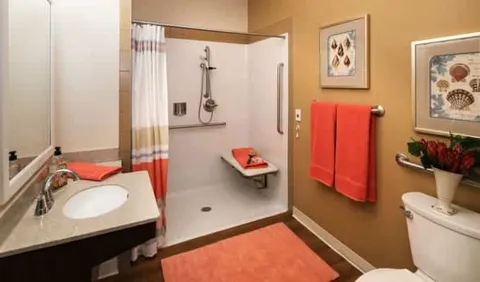 Bathroom with a shower, sink, grab rails and red towels