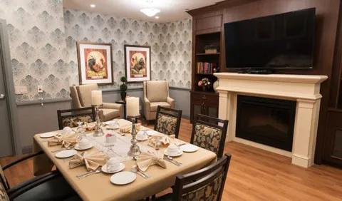 Set dining table beside a fireplace, black television and framed rooster pictures