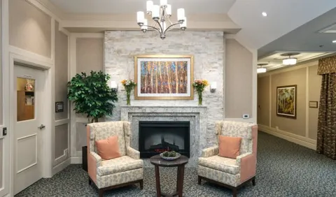 Two armchairs beside a fireplace under a woodland painting