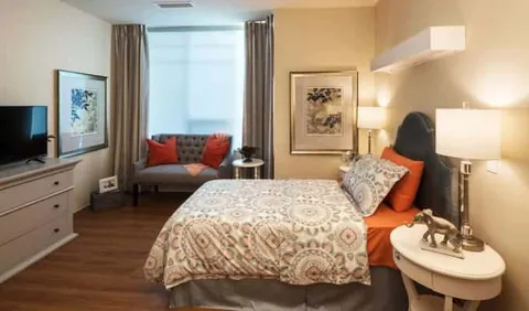 Bedroom with a patterned bedspread, lamps, a small sofa and elephant ornaments