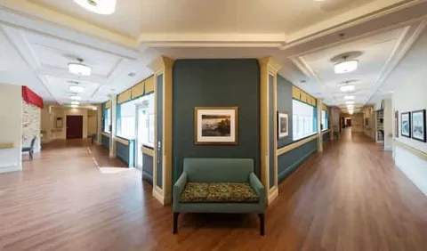 Wide hallways around a green column with a bench and framed landscape picture