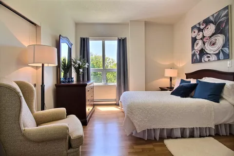 Bedroom with an armchair, mirrored dresser and floral wall art