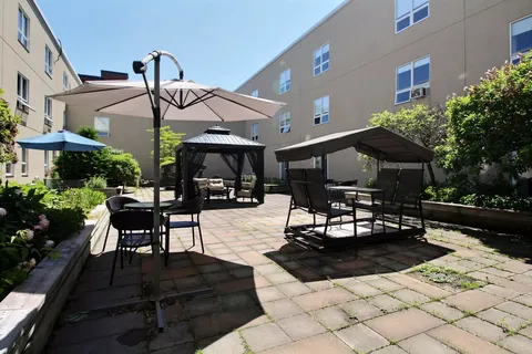 Paved courtyard with tables, umbrellas and covered swings