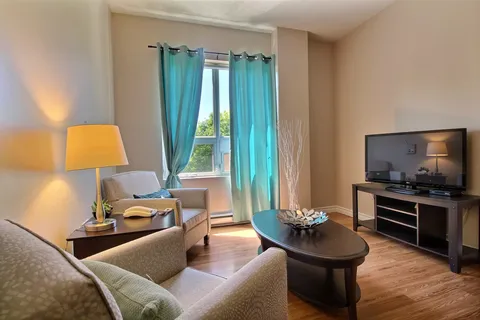 Armchairs and a coffee table beside a television and turquoise curtains
