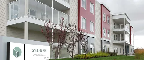 Multi-storey residence with balconies and a sign beside the front lawn