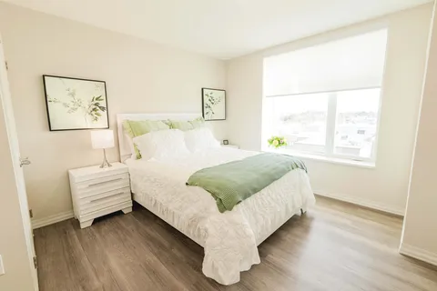 Bedroom with a white bed, pale green cushions and botanical wall art