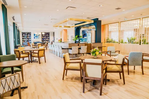 Open room with tables, chairs, bookcases and a long counter