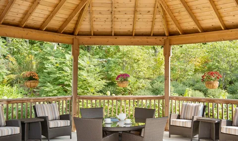 Gazebo with outdoor seating and potted flowers.