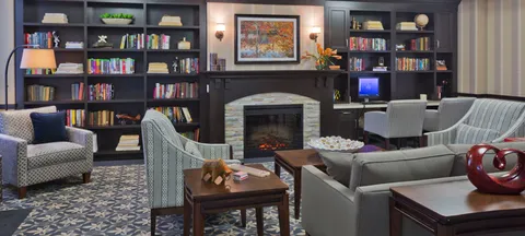 Library lounge with bookshelves, sofas, armchairs and a fireplace.