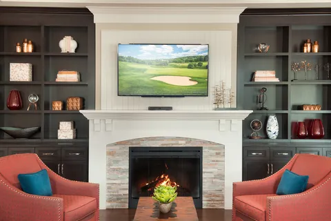 Lounge chairs beside a fireplace and built-in shelves.