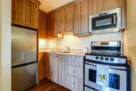 Suite kitchen with wooden cupboards, a refrigerator and a stove.