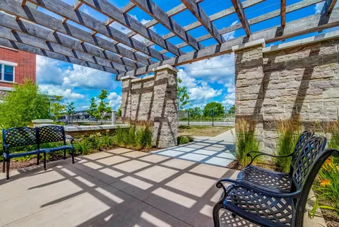 Patio benches beneath a timber pergola with stone columns.