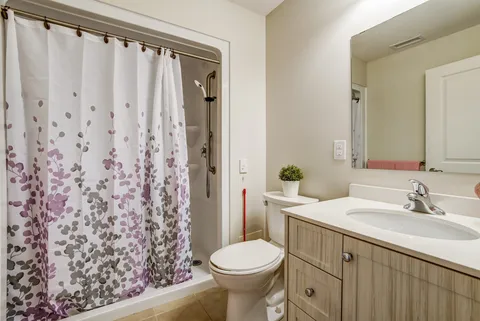 Bathroom with a vanity, toilet and curtained shower.