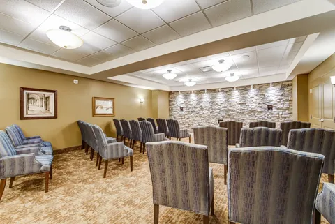 Cinema room with rows of upholstered chairs and a stone wall.