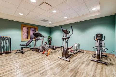 Fitness room with a treadmill, exercise bikes and an elliptical machine.