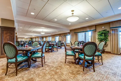 Dining room with set tables and green upholstered chairs.