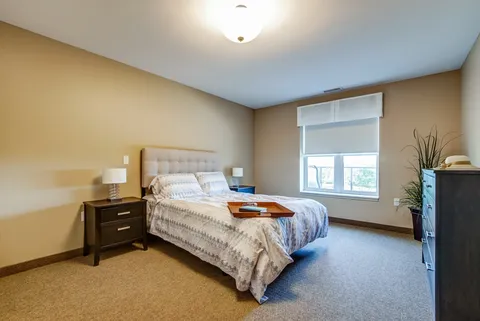Bedroom with a double bed, bedside lamps and a large window.
