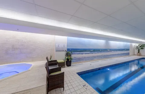 Indoor swimming pool and hot tub beside a large beach mural