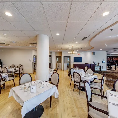 Dining tables set with white linens and rounded upholstered chairs
