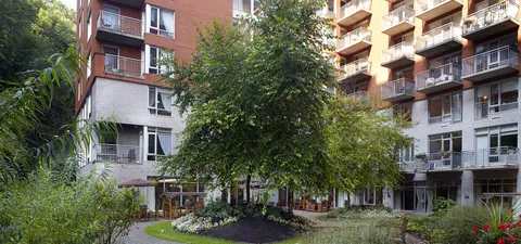 Brick building with balconies overlooking a garden and curved path