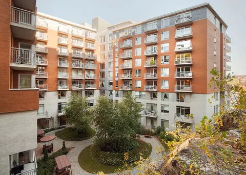 Brick residence surrounding a landscaped courtyard with paths and balconies