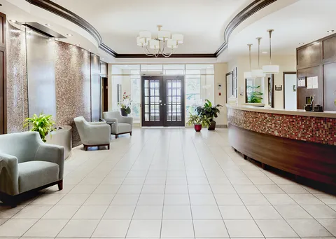 Entrance lobby with a curved reception desk, mosaic wall and glass doors