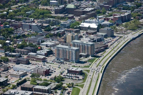 Aerial view of tall residential buildings beside a waterfront road and nearby city streets