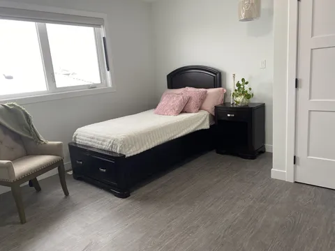 Bedroom with a bed, chair, window and wardrobe.