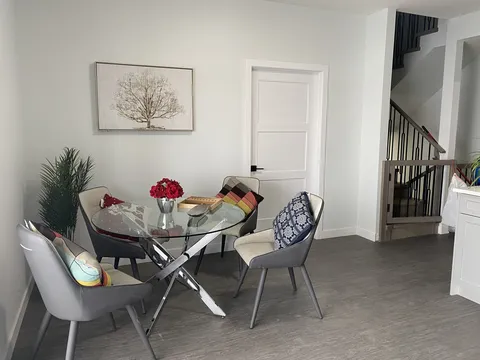 Small dining table with chairs beside a window and doorway.
