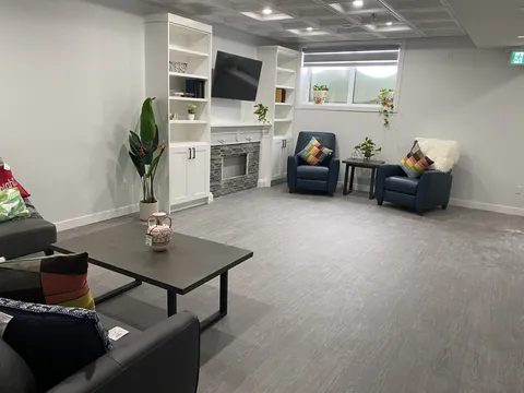 Lower-level lounge with a sofa, chairs and a fireplace.
