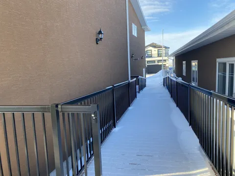 Snow-covered raised walkway with a railing beside the residence.