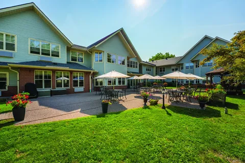 Rear of the residence beside a patio with tables and umbrellas