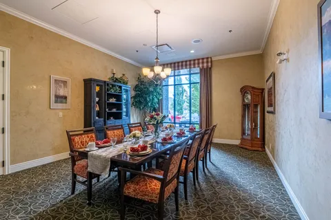 Dining room with a long set table, upholstered chairs and a grandfather clock