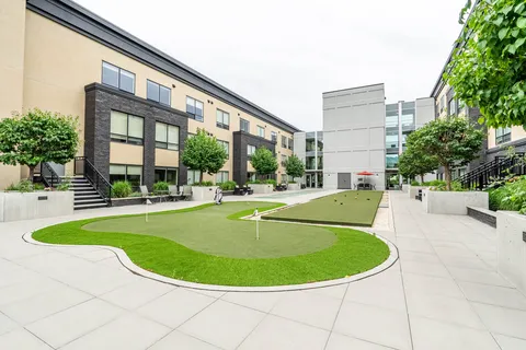 Courtyard with a putting green, paved paths, seating and raised planters