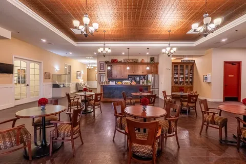 Room with round tables, wooden chairs and a counter beneath cabinets