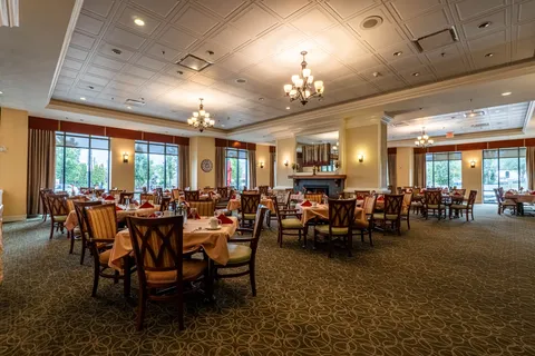 Dining room with set tables, wooden chairs, chandeliers and a fireplace