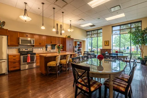 Kitchen with wooden cabinets, an island, stools and round glass tables