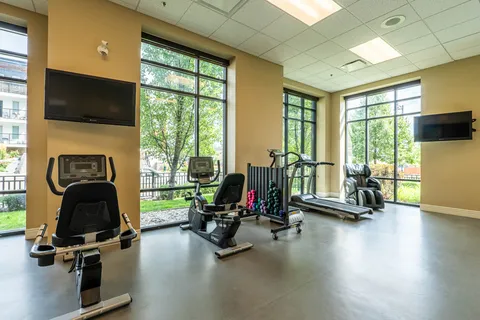 Fitness room with exercise bikes, a treadmill, dumbbells and a massage chair