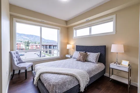 Bedroom with a bed, bedside tables, lamps, an armchair and large windows