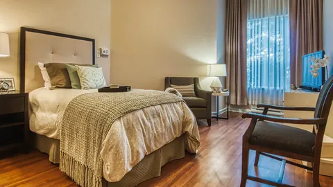 Bedroom with a bed, two armchairs, bedside lamps and a television
