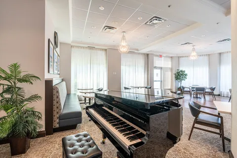 Room with a grand piano, tables, chairs and large curtained windows