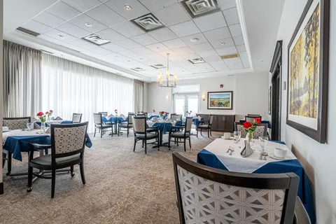 Dining room with blue tablecloths, patterned chairs and large windows