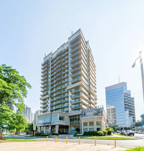 High-rise building with glass balconies, a covered entrance and landscaped frontage