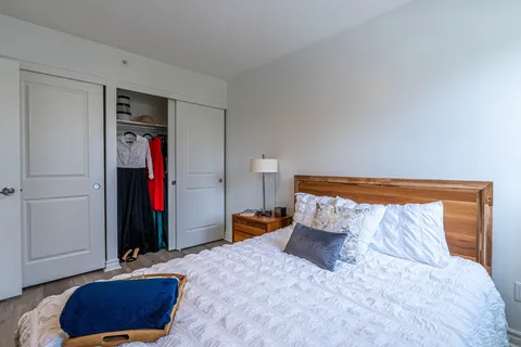 Bedroom with a wooden headboard, white bedding and a sliding-door closet