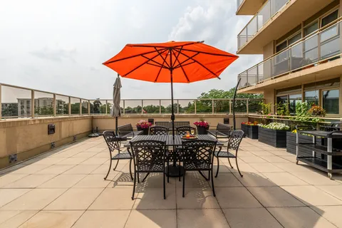 Terrace with an orange umbrella, metal tables and chairs, and flower planters